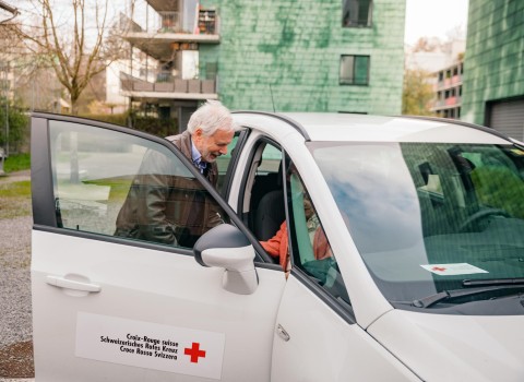 Ein freiwilliger Fahrer hilft einer Kundin aus dem Auto
